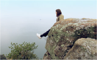 岩場で風景を眺める女性